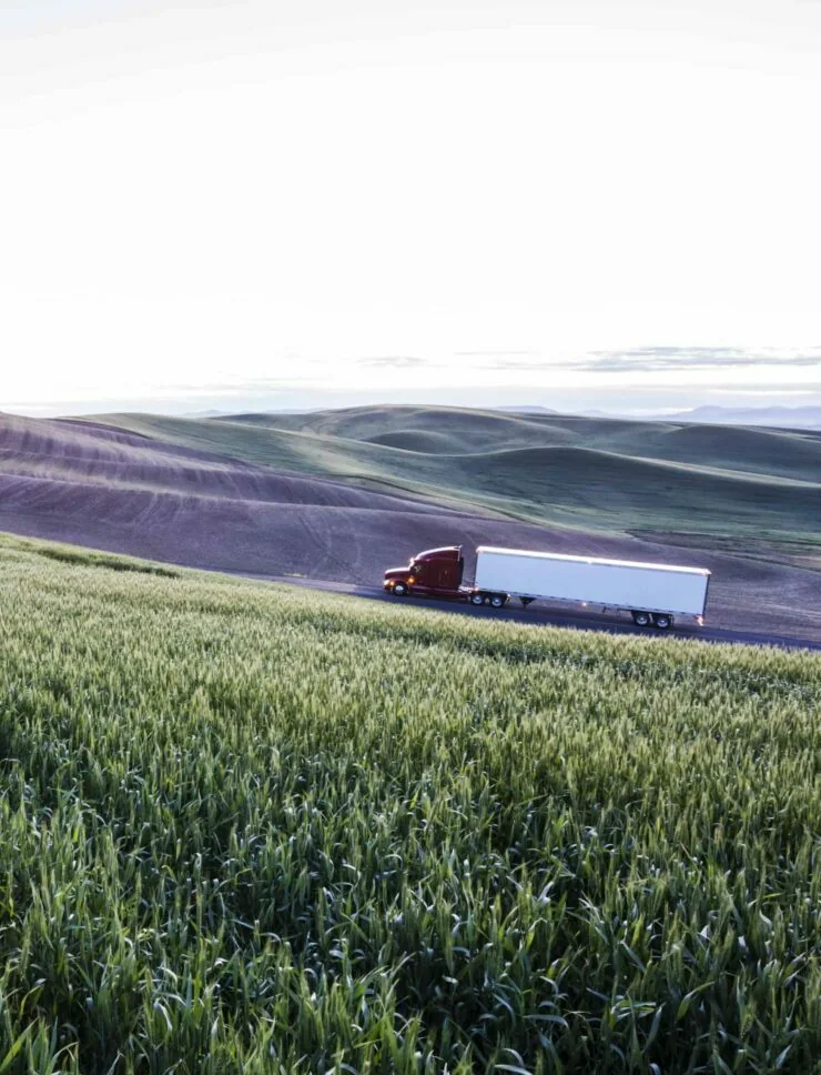 Commercial truck traveling beside open fields
